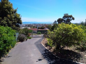 A paved driveway leading to a gated entrance with a view of a coastal landscape. - Mountain Side Golden gem (Cape Town)