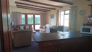 A spacious living area with a sofa, a dining table, and a kitchen counter.
