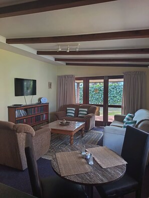 A living room with a sofa, a coffee table, a television, and a bookshelf. - Mountain Side Golden gem (Cape Town)