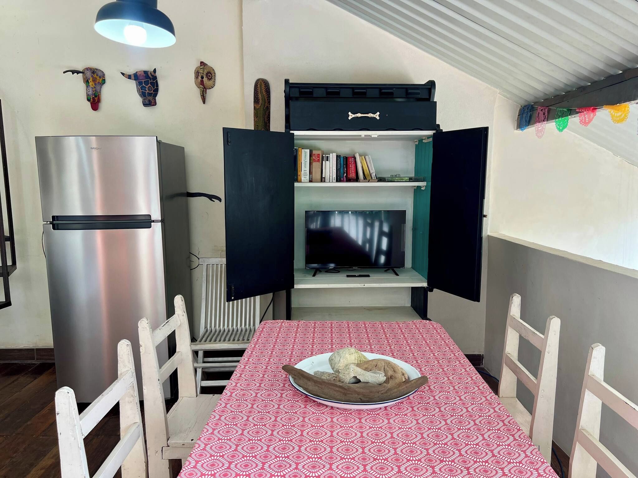 Une petite cuisine équipée d’un réfrigérateur, d’un four à micro-ondes et d’une petite étagère avec des livres.