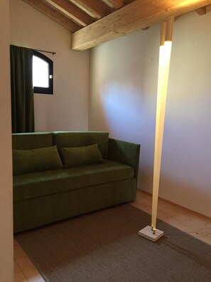 A room with a green sofa, a floor lamp, and a window with curtains. - Affitto camere con servizi bagno privati, in villa con giardino in luogo di pace (Sandrà)