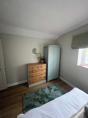 A bedroom with a wooden dresser, a wardrobe, a mirror, and a bed with a patterned rug. - Cozy Holiday Retreat in Bradford Abbas - Modern Comfort Awaits (Sherborne)