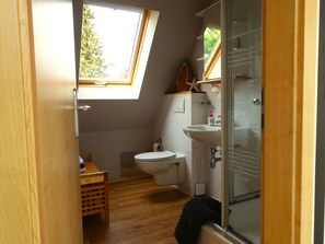 A compact bathroom with a skylight, a toilet, a sink, and a shower area. - Holiday Apartment With 2 Bedrooms (Kappeln)