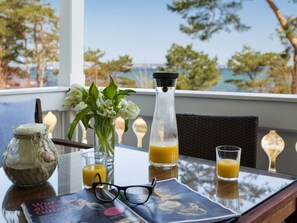 A table with a book, glasses, a vase with flowers, a candle, and two glasses of orange juice. - No. 7 in Villa Strandburg (Binz)