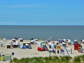 A beach with numerous beach huts and a playground area. - Holiday Apartment With 2 Bedrooms (Norden)