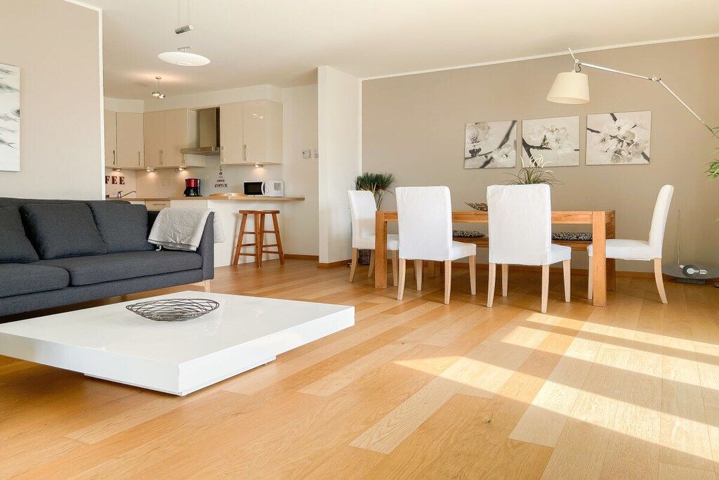 A modern living room with a sofa, coffee table, and dining area with chairs and a table.