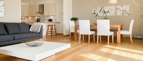 A modern living room with a sofa, coffee table, and dining area with chairs and a table.
