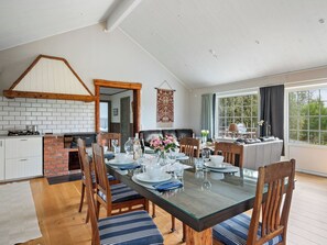 A dining area with a long table, chairs, and a view of the outdoors through large windows. - Backa Gård by Interhome (Lur)