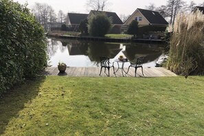 A serene outdoor area with a pond, a wooden deck, and a seating arrangement. - Holiday home Holland North (Medemblik)