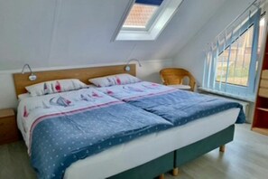 A bedroom with a bed, a chair, a skylight, and a window. - Holiday home Holland North (Medemblik)
