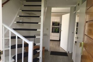 A staircase leading to a kitchen area with white cabinets and a built-in oven. - Holiday home Holland North (Medemblik)