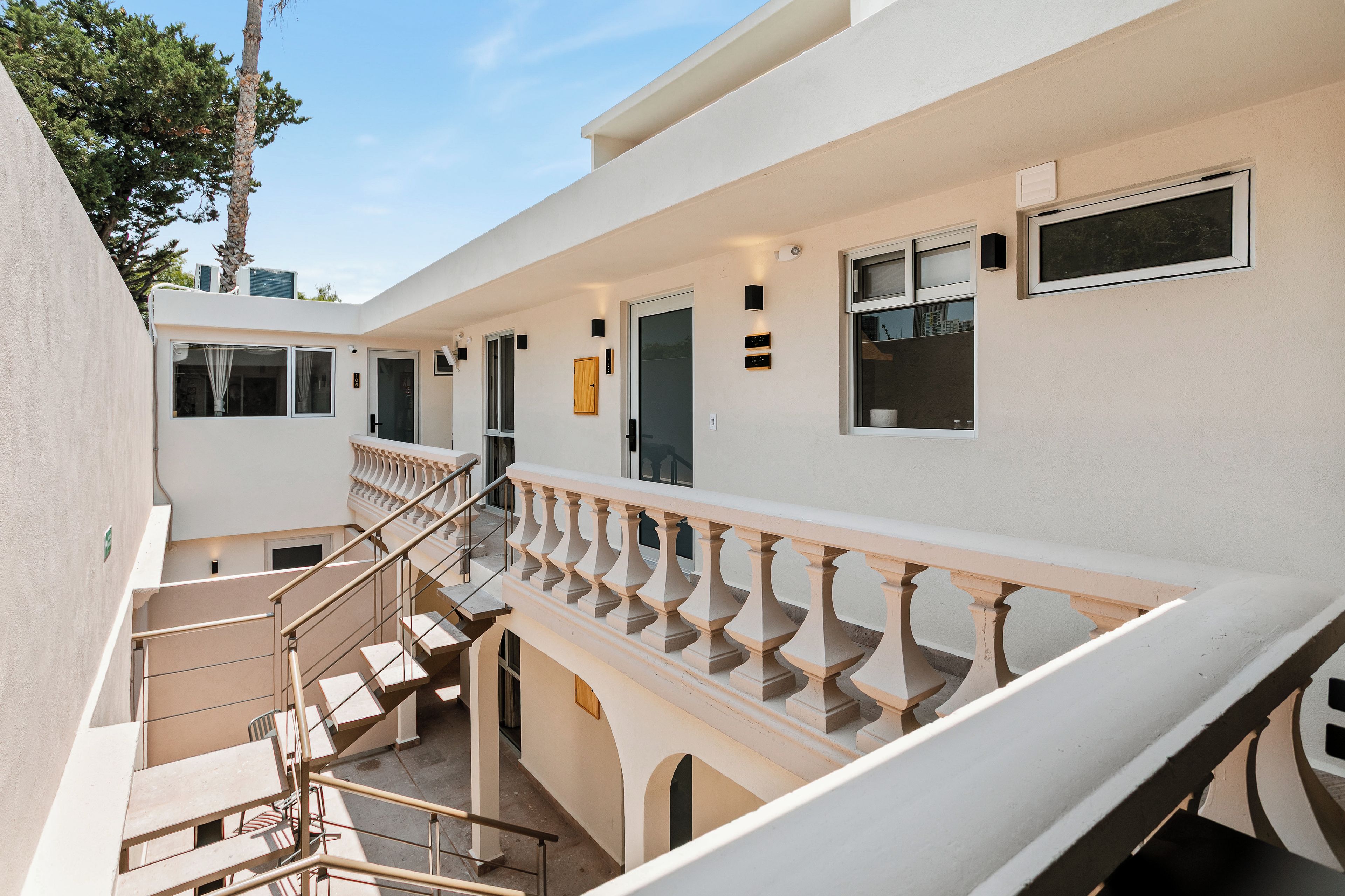 A multi-level building with a staircase, outdoor seating, and a balcony with railings.