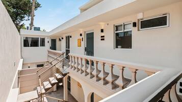 A multi-level building with a staircase, outdoor seating, and a balcony with railings.