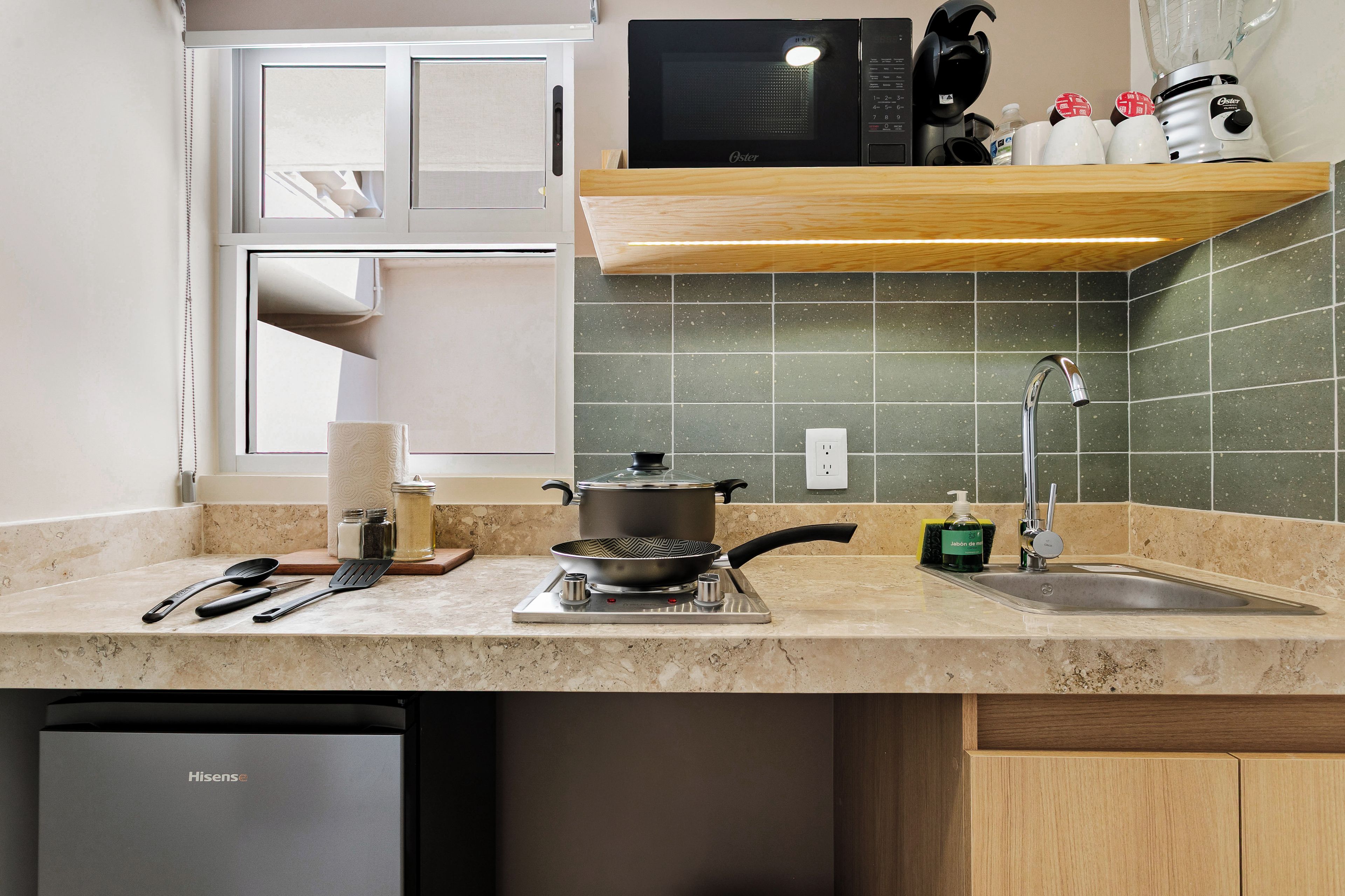 Una cocina con estufa, lavabo y diversos utensilios.