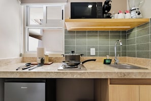 Una cocina con estufa, lavabo y diversos utensilios.
