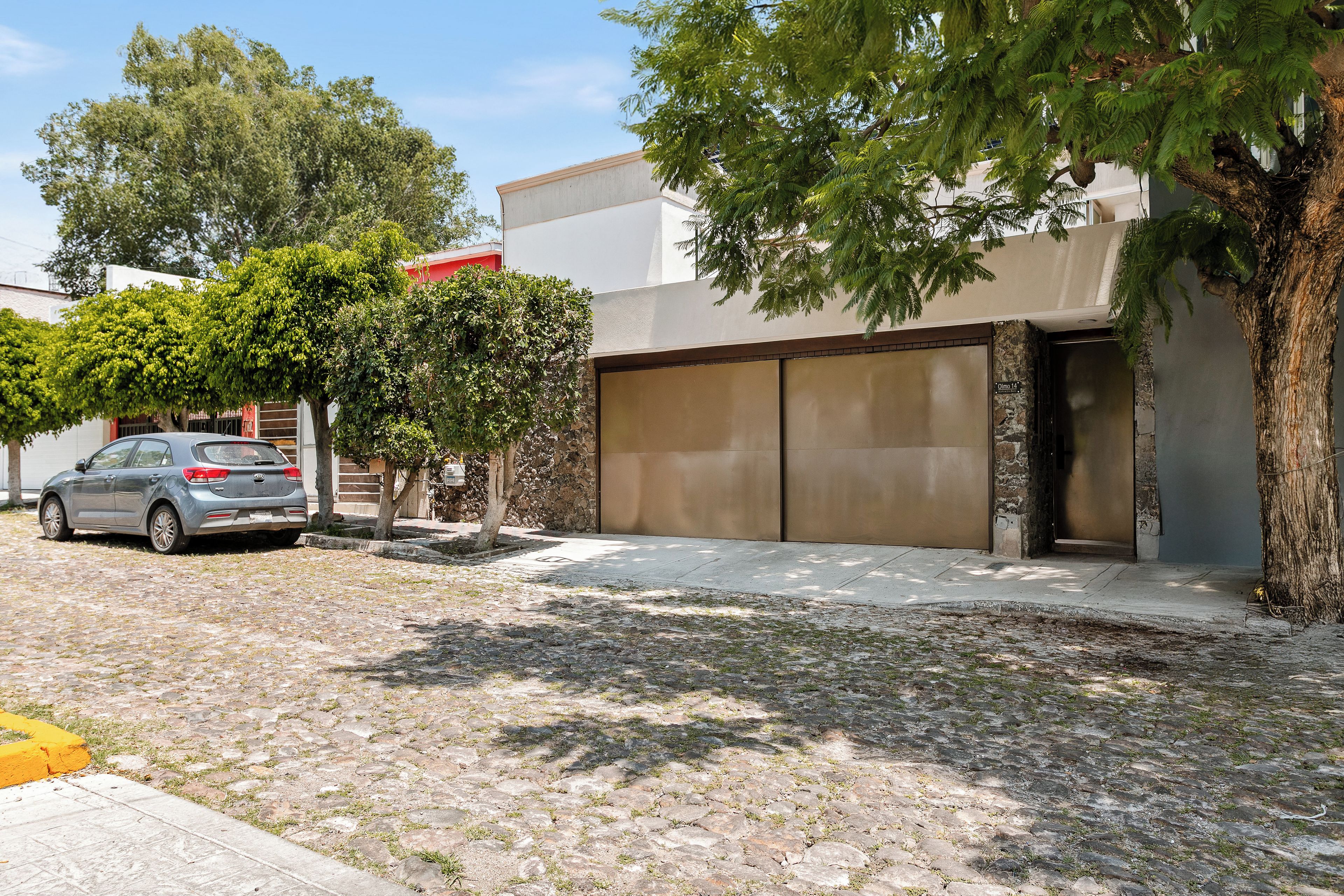 Zona residencial con camino de entrada pavimentado, un coche aparcado y puerta de garaje.