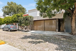 Zona residencial con camino de entrada pavimentado, un coche aparcado y puerta de garaje.
