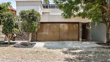 A residential garage with a brown door, a stone wall, and a tree in the foreground.