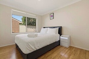 Une chambre à coucher avec un lit, une table de chevet, une fenêtre et un tableau au mur.