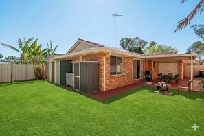 A residential property with a brick house, a fenced yard, and a barbecue area. - The Wattle House - Your Home Away from Home (Wattle Grove)
