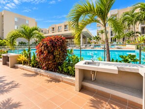 A swimming pool with a view of a hotel building, surrounded by palm trees and a small garden area. - Experience Cartagena History Caribbean Flavors and Relaxation in Serena del Mar (Cartagena Province)