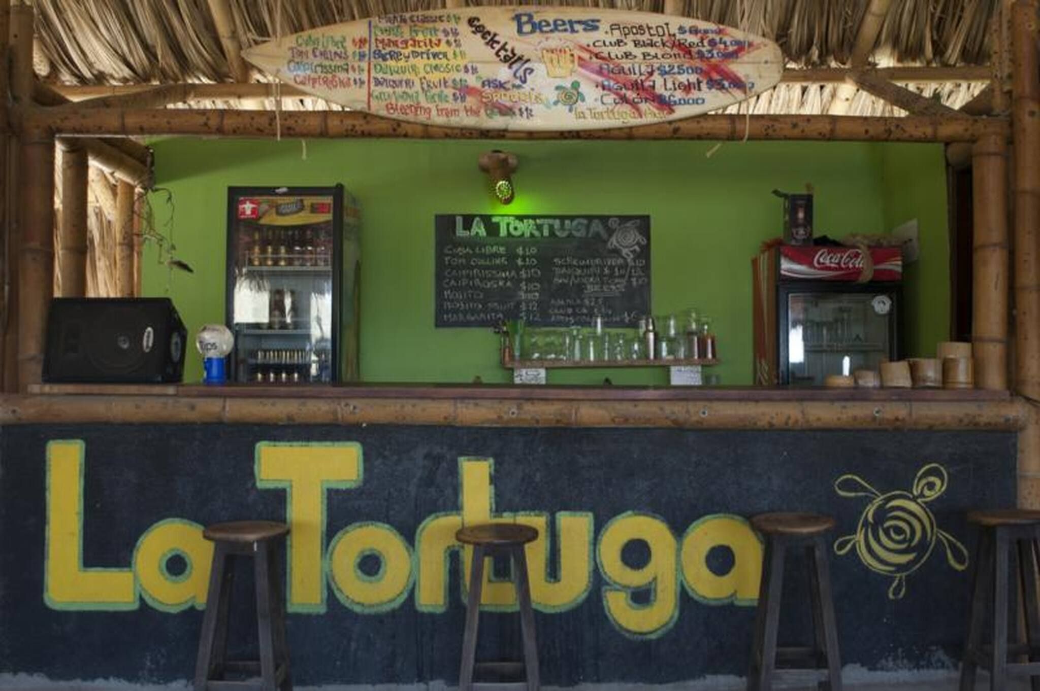 Un bar appelé «La Tortuga», avec un tableau noir servant de menu, un réfrigérateur et un distributeur de Coca-Cola.