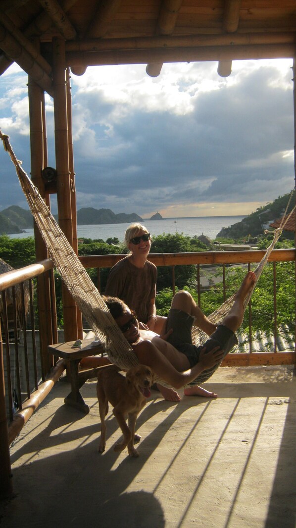 A wooden deck with a hammock, a dog, and a view of the sea and mountains. - Private room - 4 people, pool & sea view (Santa Marta)
