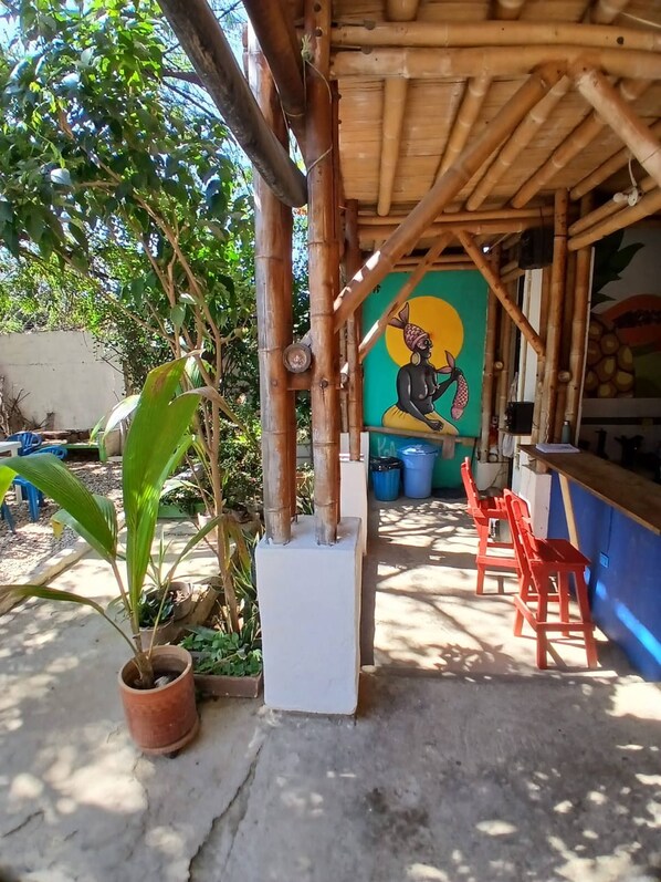 A covered outdoor area with a mural, potted plants, and red chairs. - House with private pool and bbq (Taganga)