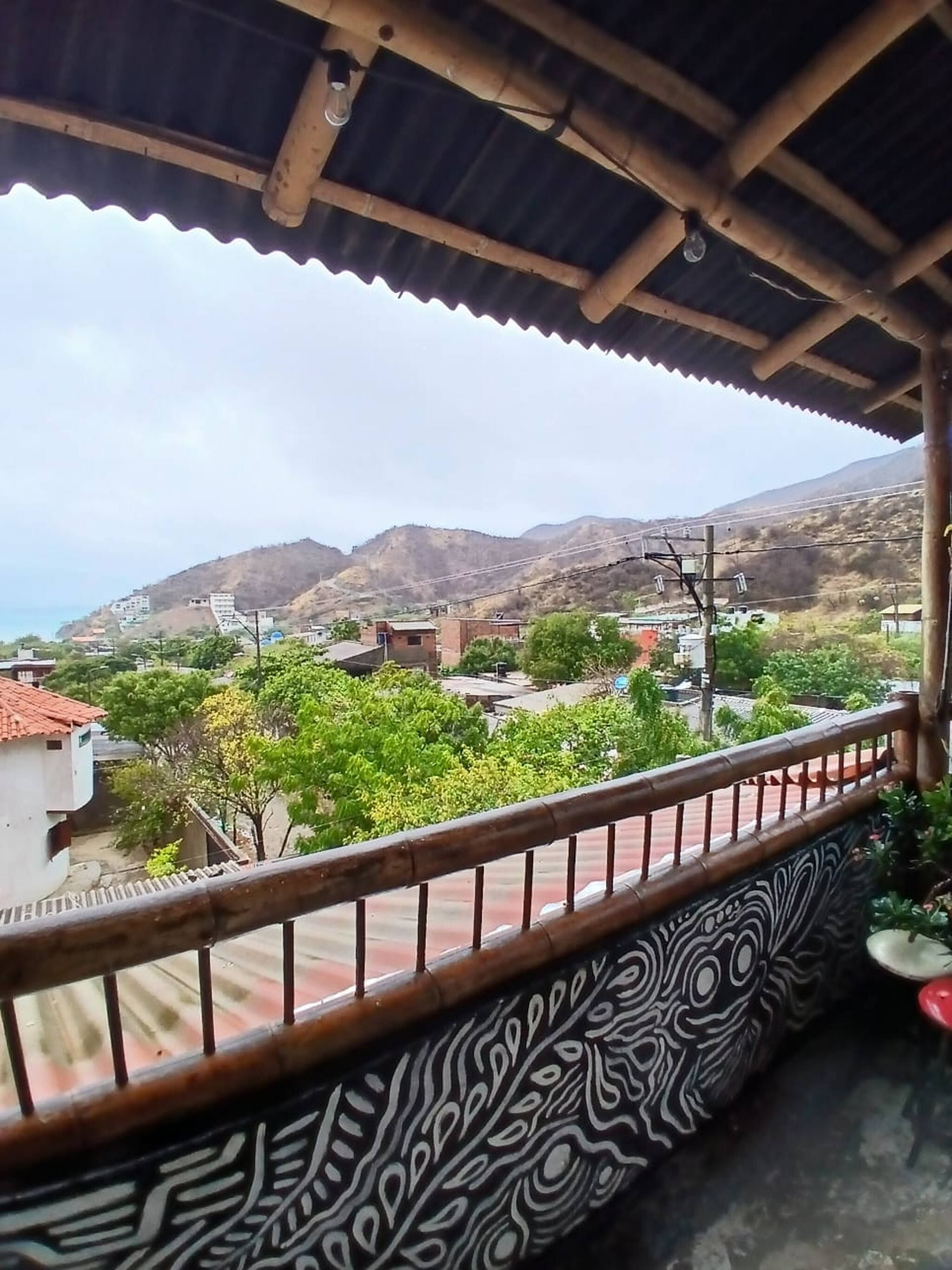 A balcony with a patterned floor, overlooking a residential area with houses and hills.