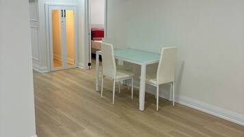 Una habitación con una mesa de comedor y sillas, una cama con un cojín rojo y un armario blanco.