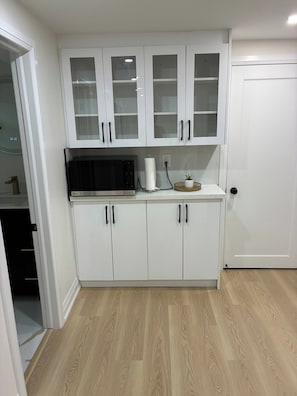 Una cucina con pensili bianchi, un forno a microonde e un cesto con una pianta.