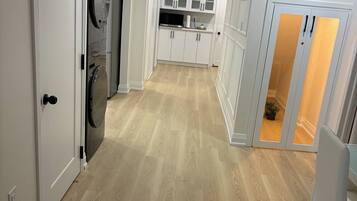 A modern kitchen with white cabinets, a built-in oven, and a stainless steel refrigerator.