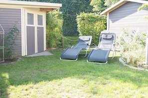 A backyard with two sun loungers, a shed, and a house. - Holiday home with 3 bedrooms (Timmendorfer Strand \/ Niendorf)