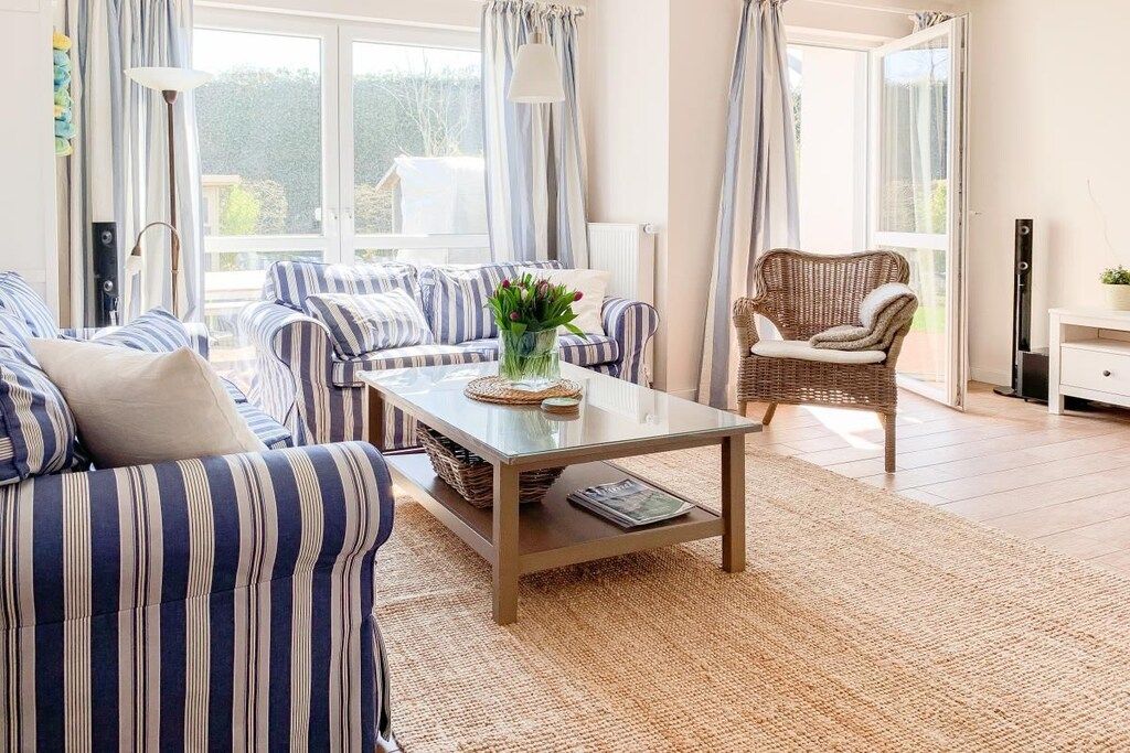 A living room with striped sofas, a coffee table, and a wicker chair.