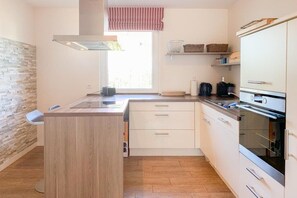 A compact kitchen with a central island, white cabinetry, and a window with a view. - Holiday home with 3 bedrooms (Timmendorfer Strand \/ Niendorf)