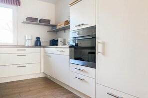 A kitchen with white cabinets, a built-in oven, and a coffee maker. - Holiday home with 3 bedrooms (Timmendorfer Strand \/ Niendorf)