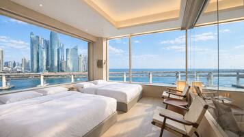 A modern hotel room with a city skyline view, a balcony with seating, and a large window.