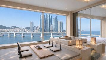 A modern hotel room with a large window offering a city view, a seating area with cushions, and a small table with a tray.
