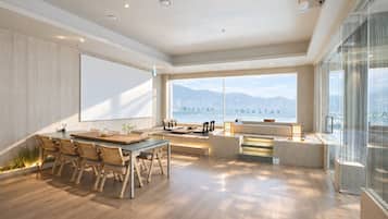 A modern hotel room with a large window, a dining area, and a seating space.