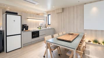 Una cocina moderna con horno empotrado, cafetera y comedor con mesa y sillas de madera.