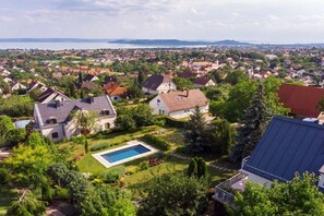 A residential area with houses, a swimming pool, and a view of a body of water.