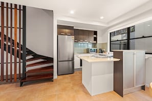 Una cocina moderna con isla integrada, electrodomésticos de acero inoxidable y una escalera de madera.