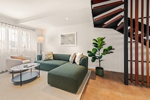 Una sala moderna con un sofá modular, una mesa de centro redonda y una planta en maceta.