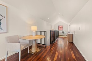 A modern interior with a round wooden table, a grey armchair, and a white sofa. - Spacious 3-Level Windsor Townhouse | 2 Carparks (Brisbane)