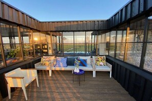 Een overdekt terras met uitzicht op een veld.