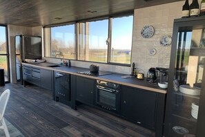 A modern kitchen with a large window, built-in appliances, and a view of the outdoors. - Houseboat with 3 bedrooms (Oostknollendam)