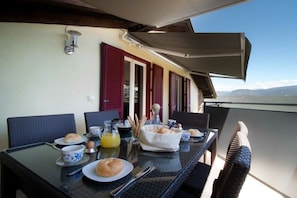 An outdoor dining area with a table set for breakfast, including bread, eggs, and juice. - Melanie's Guesthouse (Kaltern)