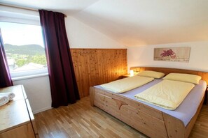 Une chambre à coucher avec un lit en bois, une table de chevet, une fenêtre avec des rideaux et un tableau accroché au mur.