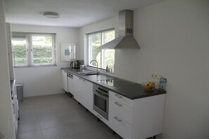 A modern kitchen with white cabinets, stainless steel appliances, and a black countertop. - Holiday home with 1 bedroom (Oostkapelle)
