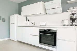 Eine moderne Küche mit weißen Schränken, einem Backofen, einer Kaffeemaschine und einer Mikrowelle.
